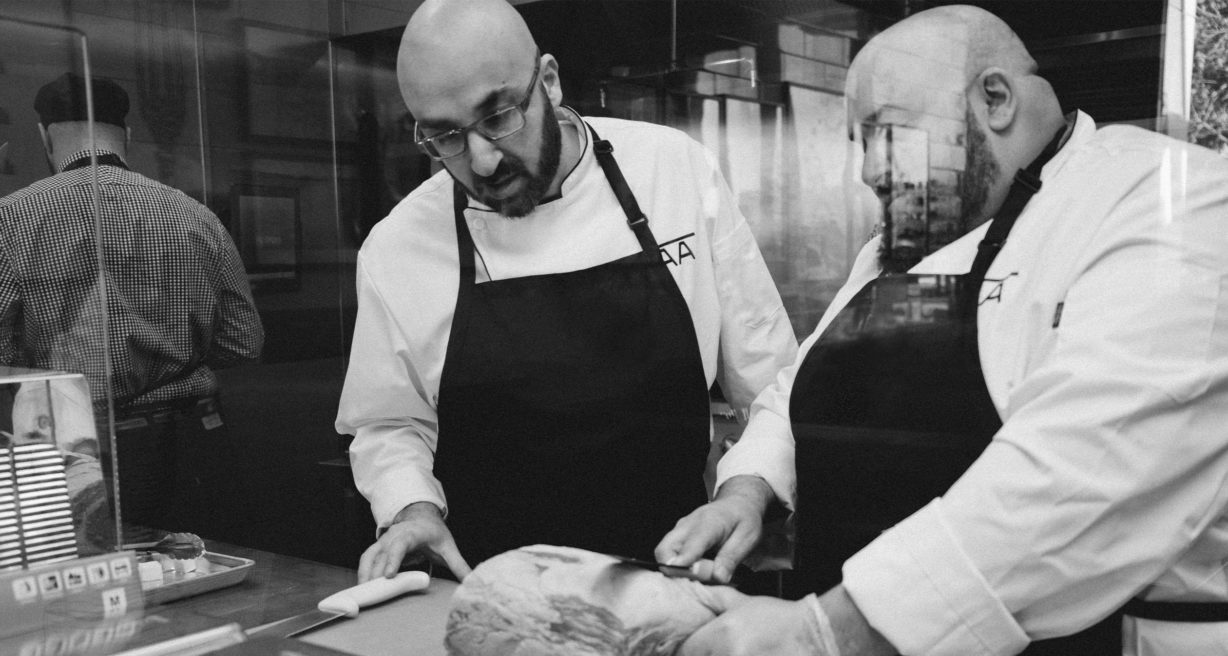 Two chefs cutting meat